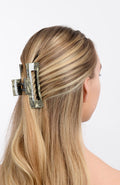 large hair clip with a cutout design holding hair up in a half up half down hair style